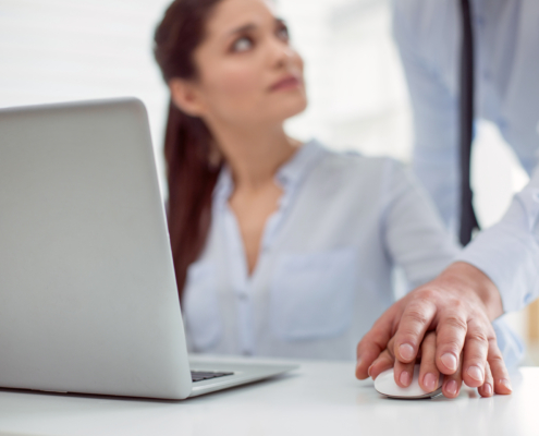 Sexual abuse. Nice pleasant young woman sitting at the table and working while feeling a male hand on hers