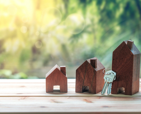 Three little wooden houses with a key hanging on the end of the third house