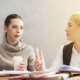 Two women sitting at a table and talking to each other