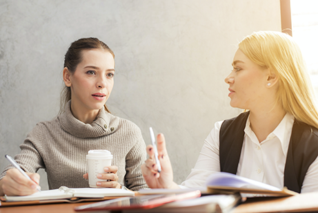 Two women sitting at a table and talking to each other