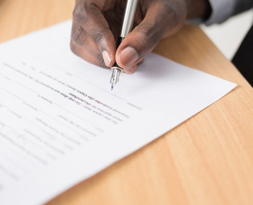 Someone signing a contract with a pen