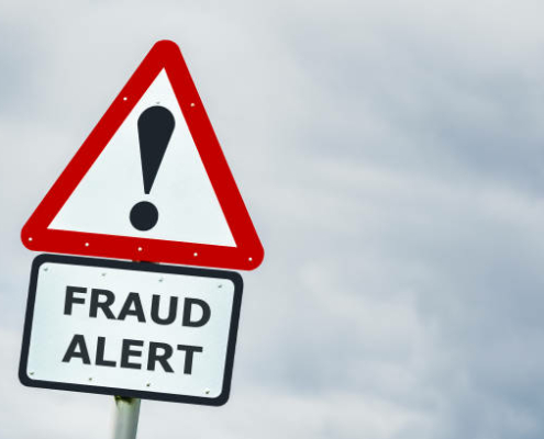 Conceptual triangular hazard road sign against a stormy sky saying fraud alert