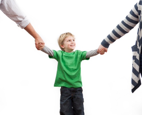 Two parents holding their child's hands