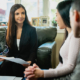 Woman financial advisor talking to married couple in the living room of their home.