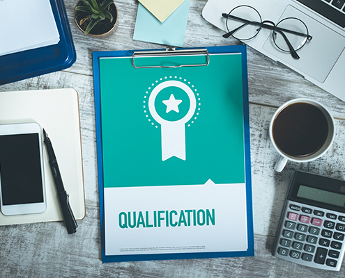 A desk with a clipboard reading 'qualification'