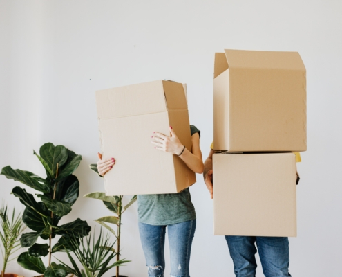 Two people carrying cardboard boxes