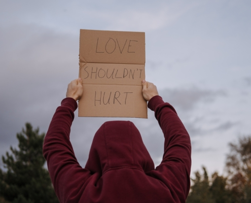 "Love shouldn't hurt" cardboard sign